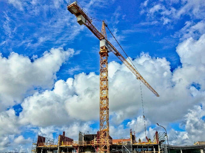 yellow crane under blue sky and white clouds during daytime